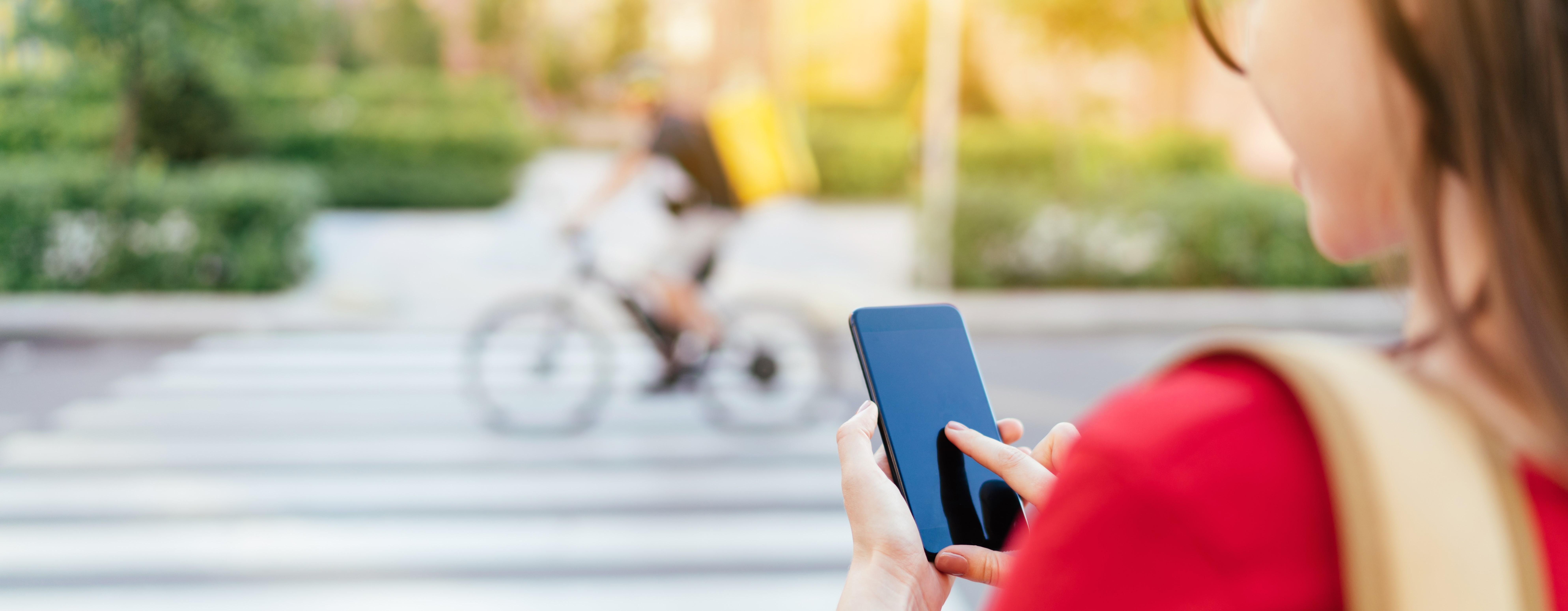 young woman in front of pedestratian crossing using her phone for navigation support